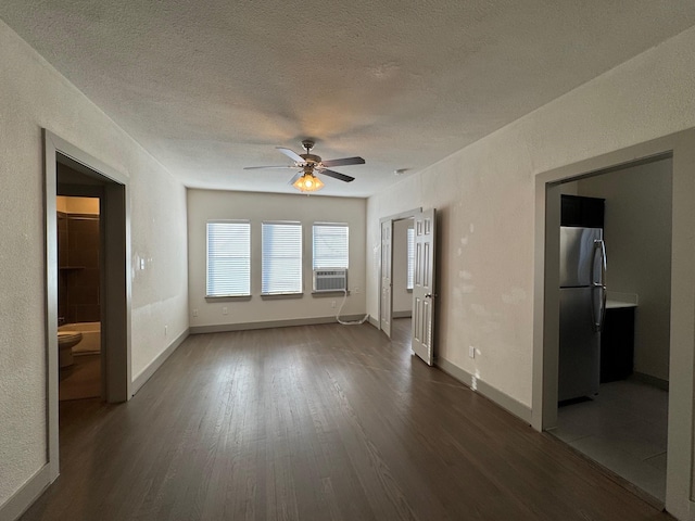 spare room featuring a textured ceiling, dark wood finished floors, and baseboards