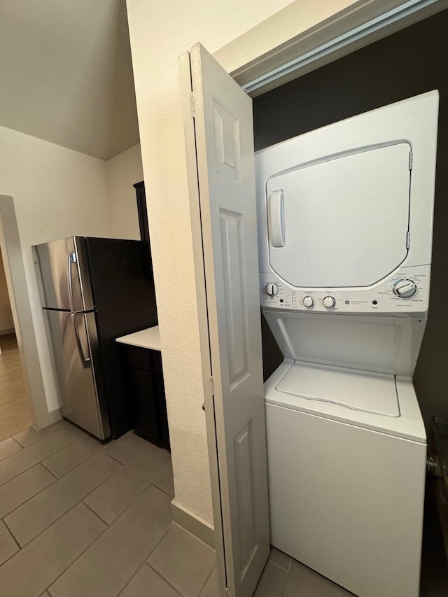 laundry room featuring laundry area, light tile patterned floors, and stacked washer / drying machine