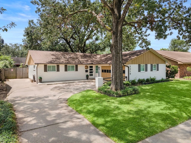 ranch-style home featuring an attached garage, brick siding, fence, driveway, and a front lawn