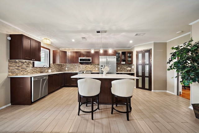 kitchen featuring stainless steel appliances, light countertops, visible vents, dark brown cabinets, and a kitchen bar