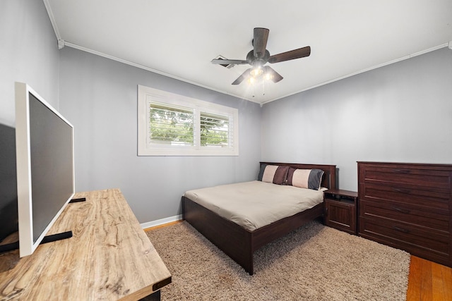 bedroom featuring ceiling fan, crown molding, baseboards, and wood finished floors