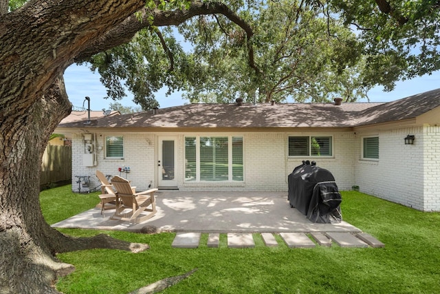 back of house featuring a patio area, fence, a lawn, and brick siding