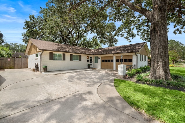 single story home with driveway, brick siding, an attached garage, and fence