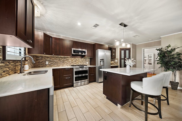 kitchen with a breakfast bar area, stainless steel appliances, a sink, visible vents, and a center island