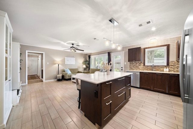 kitchen with stainless steel appliances, visible vents, light countertops, dark brown cabinets, and tasteful backsplash