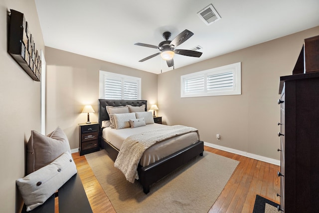 bedroom with light wood-style floors, visible vents, ceiling fan, and baseboards