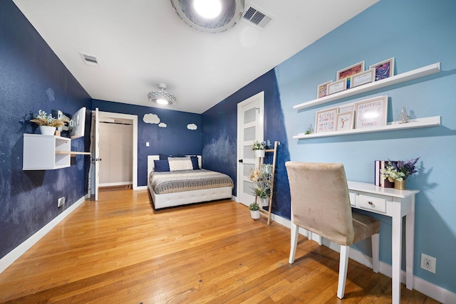 bedroom with wood-type flooring, visible vents, and baseboards