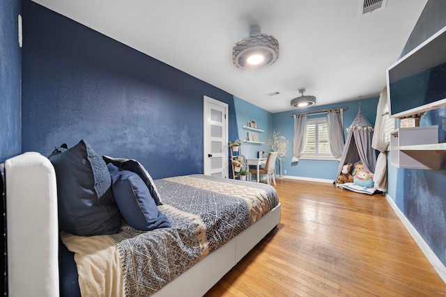 bedroom with visible vents, hardwood / wood-style flooring, and baseboards