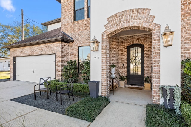 doorway to property featuring a garage, concrete driveway, brick siding, and roof with shingles