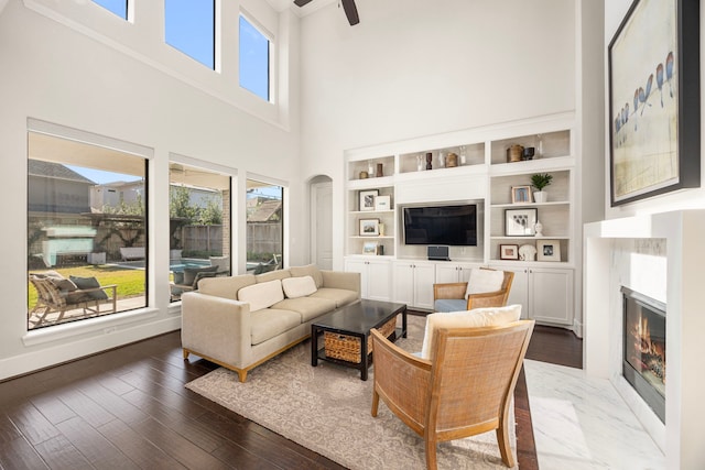 living area featuring dark wood-style floors, a fireplace, plenty of natural light, and ceiling fan