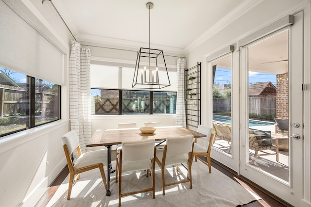 dining room with a healthy amount of sunlight, baseboards, crown molding, and wood finished floors