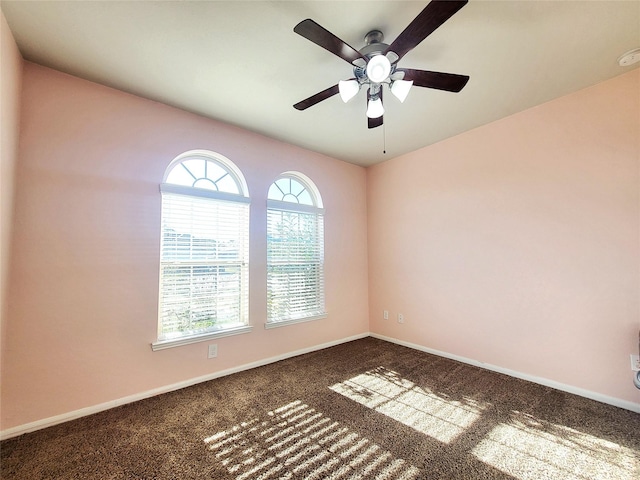 carpeted spare room featuring a ceiling fan and baseboards