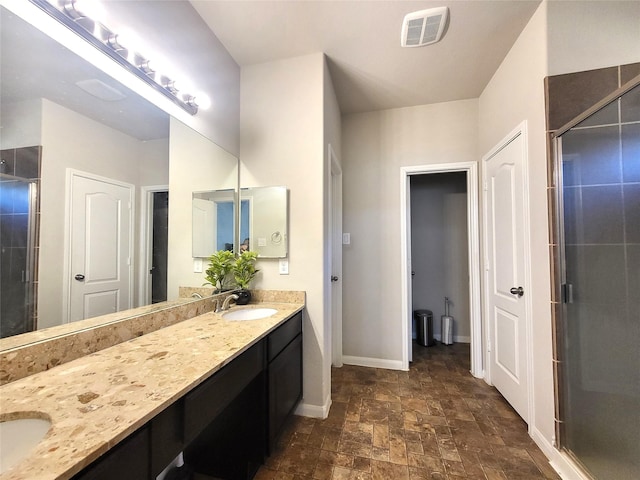 full bath with a sink, visible vents, baseboards, double vanity, and a stall shower