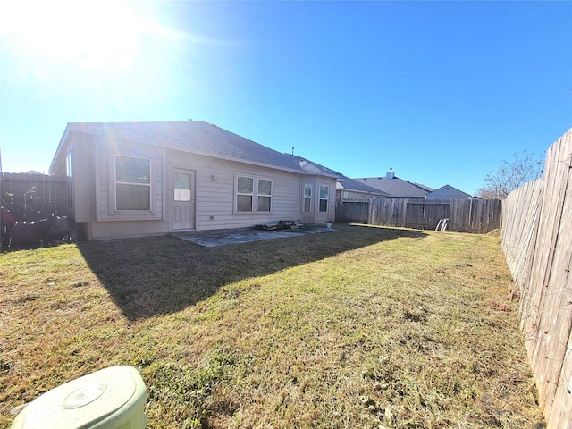 rear view of property with a fenced backyard and a lawn