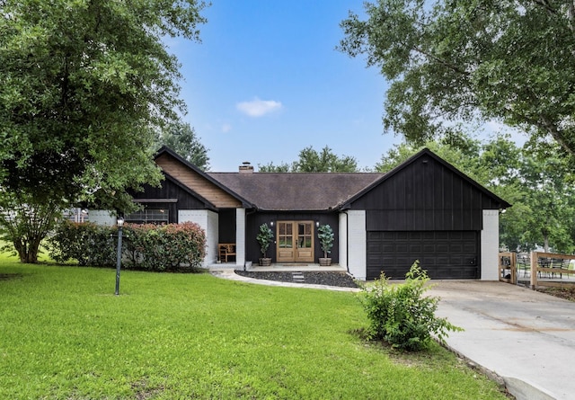 view of front of home with a garage, concrete driveway, a chimney, a front lawn, and brick siding