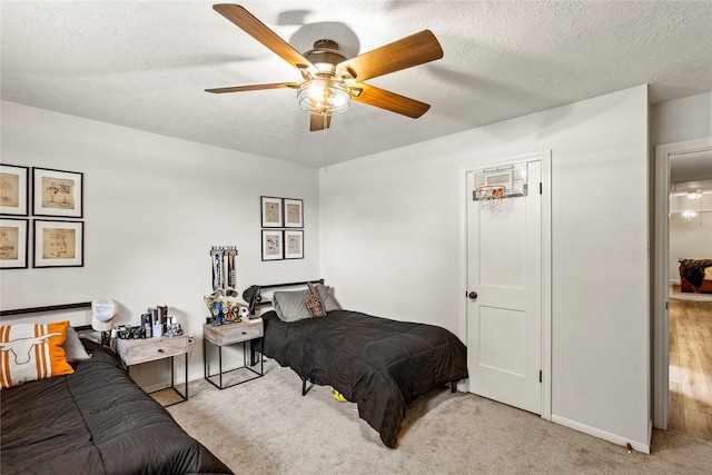 carpeted bedroom featuring ceiling fan, baseboards, and a textured ceiling