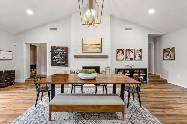 dining area with a chandelier, visible vents, a fireplace, and wood finished floors