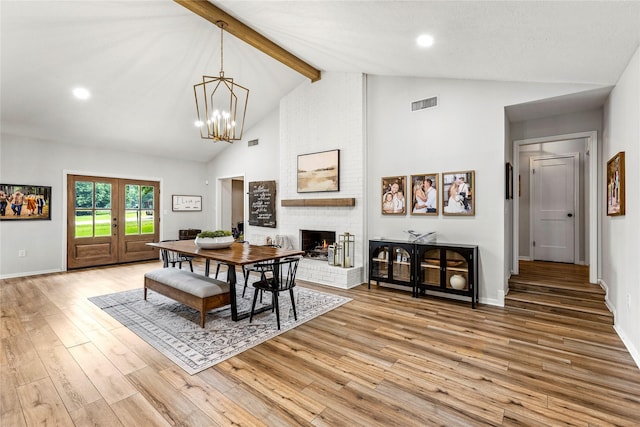 dining room with a fireplace, visible vents, light wood-style floors, french doors, and beamed ceiling