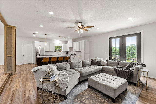 living area featuring a textured ceiling, french doors, light wood-type flooring, and recessed lighting