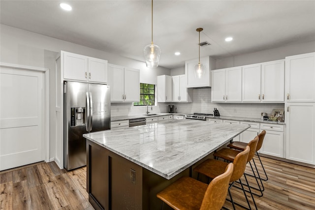 kitchen with appliances with stainless steel finishes, a sink, white cabinetry, and a center island