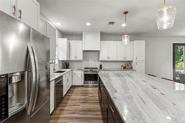 kitchen with decorative backsplash, light stone countertops, custom exhaust hood, stainless steel appliances, and a sink