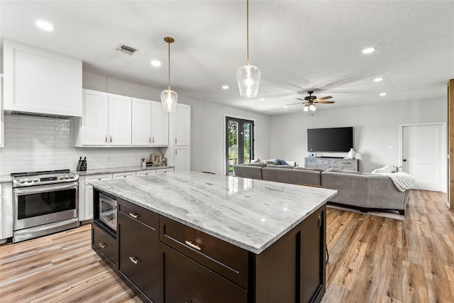 kitchen with stainless steel appliances, visible vents, light wood-style floors, white cabinets, and tasteful backsplash