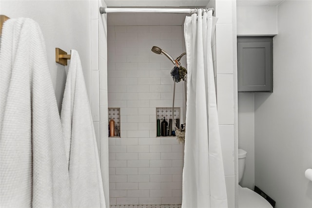 bathroom featuring a tile shower and toilet