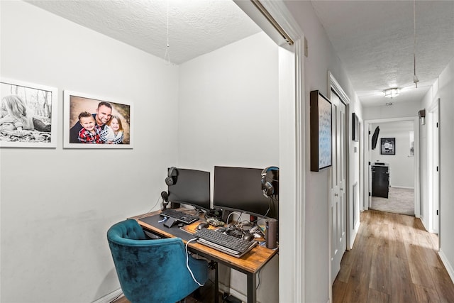 home office with a textured ceiling, wood finished floors, and baseboards