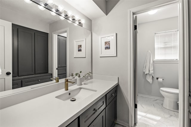 bathroom featuring marble finish floor, baseboards, vanity, and toilet