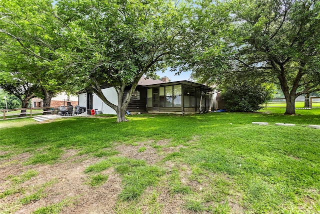 view of yard featuring a patio area, fence, and glass enclosure