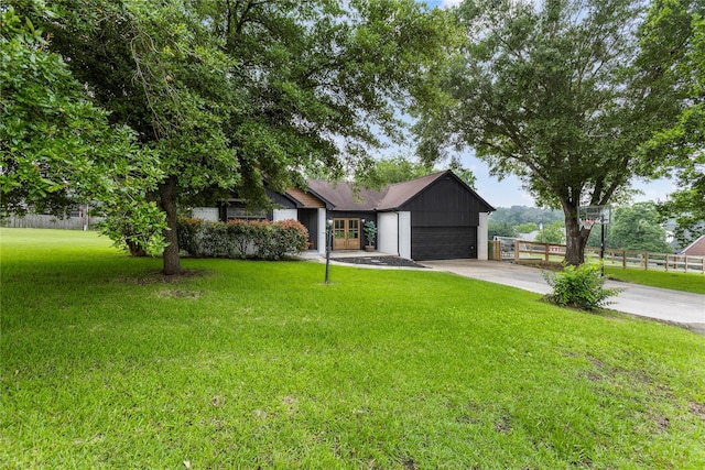 view of front of property featuring a garage, concrete driveway, fence, a front lawn, and board and batten siding