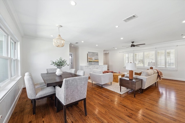 dining room with baseboards, visible vents, wood finished floors, crown molding, and recessed lighting