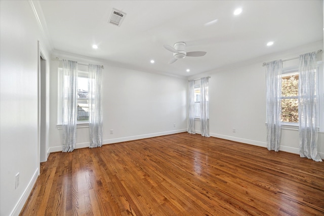 empty room featuring ornamental molding, a healthy amount of sunlight, visible vents, and wood finished floors