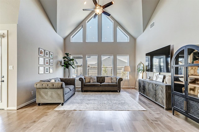 living room featuring visible vents, baseboards, ceiling fan, wood finished floors, and high vaulted ceiling