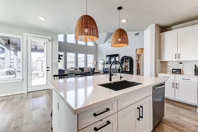 kitchen featuring visible vents, light wood-type flooring, a sink, stainless steel dishwasher, and backsplash