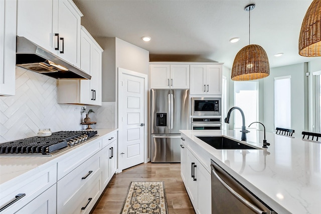 kitchen with light wood-style flooring, a sink, stainless steel appliances, under cabinet range hood, and white cabinetry