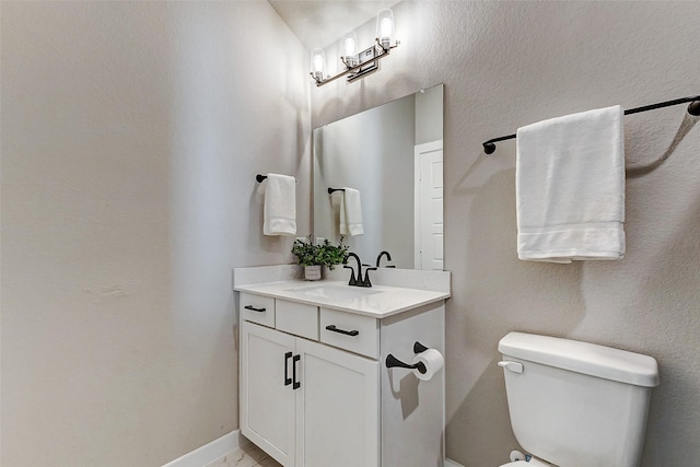 half bathroom with vanity, toilet, and baseboards