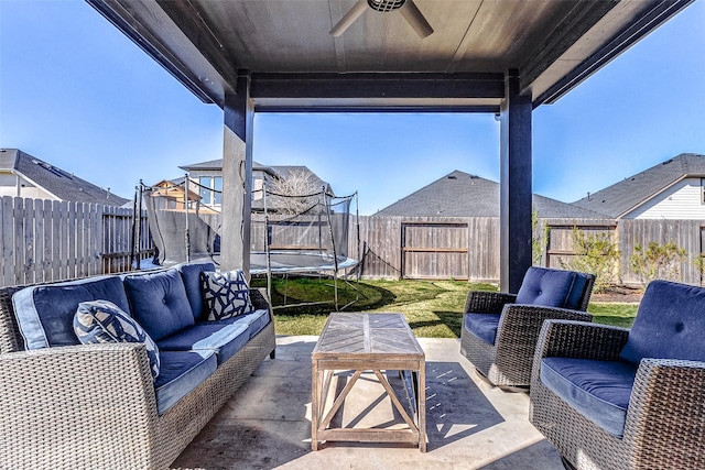 view of patio / terrace featuring a ceiling fan, an outdoor living space, a trampoline, and a fenced backyard