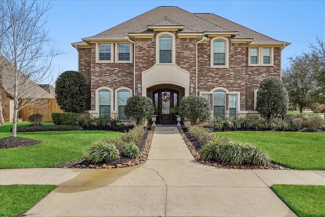 french country inspired facade featuring brick siding and a front yard