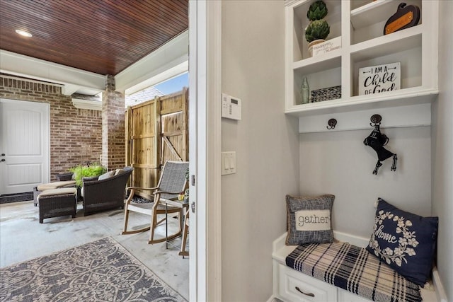 mudroom with wood ceiling and brick wall