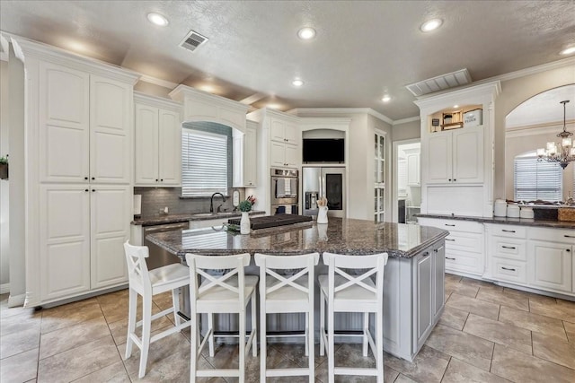 kitchen with a sink, appliances with stainless steel finishes, a kitchen bar, and visible vents