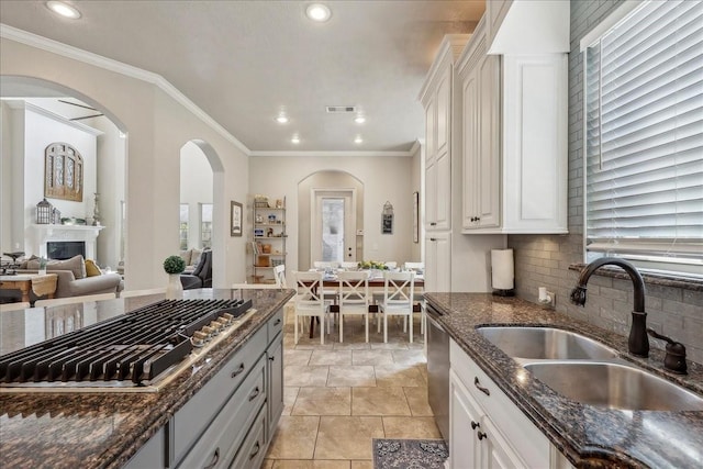 kitchen featuring visible vents, decorative backsplash, appliances with stainless steel finishes, a sink, and dark stone countertops