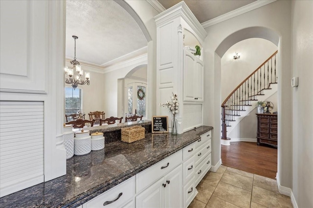 kitchen with ornamental molding, white cabinetry, baseboards, and light tile patterned flooring