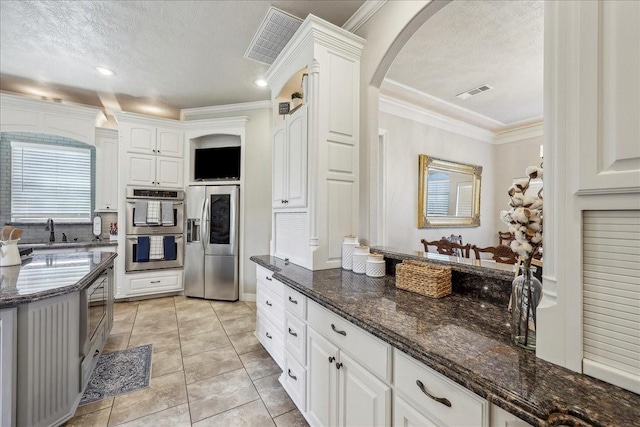 kitchen featuring appliances with stainless steel finishes, arched walkways, visible vents, and crown molding