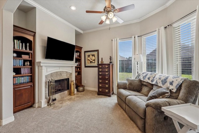 carpeted living area with ornamental molding, baseboards, a tiled fireplace, and a ceiling fan