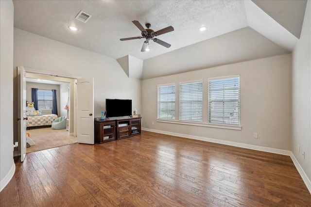 living area featuring lofted ceiling, hardwood / wood-style flooring, plenty of natural light, and visible vents