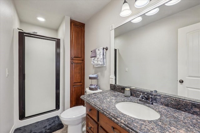 bathroom featuring toilet, a shower stall, and vanity