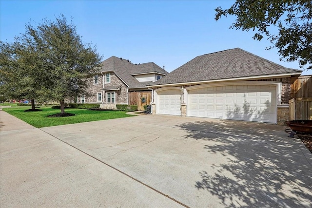 traditional home featuring roof with shingles, concrete driveway, a garage, stone siding, and a front lawn