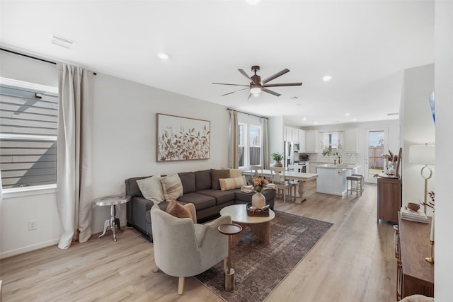 living area featuring a ceiling fan, light wood-type flooring, visible vents, and recessed lighting