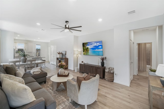 living area with light wood-style floors, recessed lighting, visible vents, and baseboards